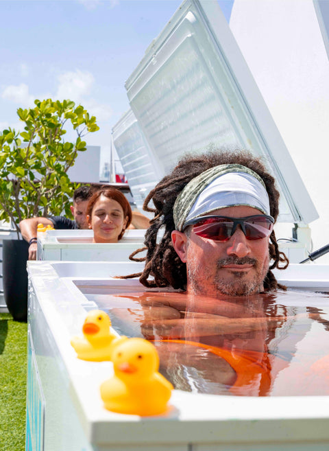 Lifestyle photo of man in rooftop ice bath at Miami Ice Club with yellow rubber ducks