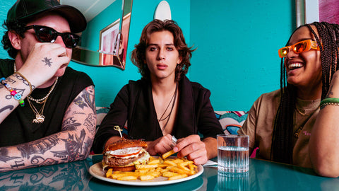Lifestyle food photography of friends sharing a burger and fries in a Miami diner