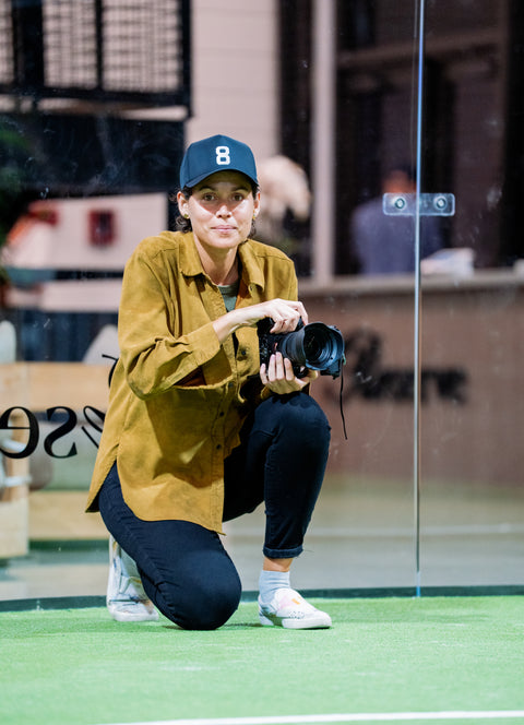 Portrait of Miami creative art director Anyelika Perez kneeling with camera at Reserve Soleil Mia padel court